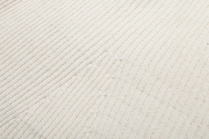 Gros plan du tissu en maille côtelée blanc cassé montrant la texture douce de la robe