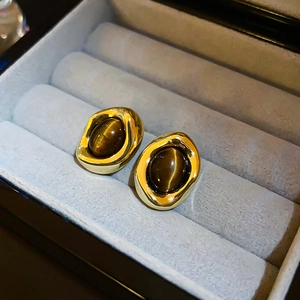 Macro detail of vintage gold-plated earrings with tiger eye stones in a velvet box