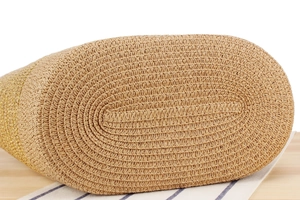 Detail view of oval straw tote base with golden thread and woven plant fiber texture