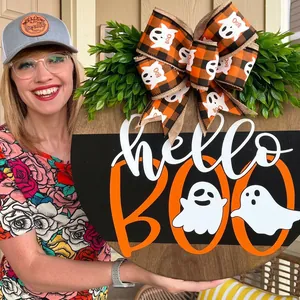 Wooden Halloween door hanger with orange BOO text, ghosts, and large plaid bow decoration
