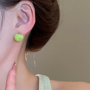Macro detail of a green apple earring with gold leaf and star on a model's ear