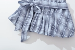 Close-up of blue gingham skirt waist featuring a stylish decorative bow tie detail