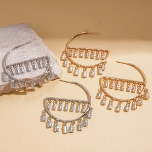Detail of gold and silver semi-circle earrings with dangling zircon fringe on stone