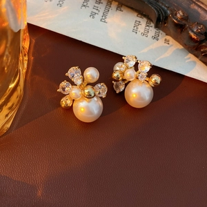 Detailed close-up of pearl flower earrings with gold metal and sparkling cubic zirconia