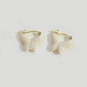 Detail of butterfly drop earrings featuring cream glitter wings and gold metal clasps