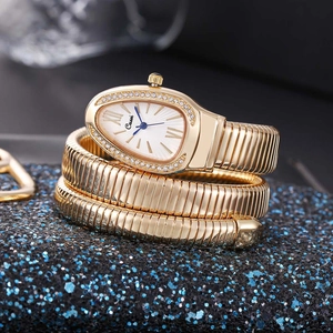 Close-up of golden snake watch with teardrop dial and blue hands on glitter base