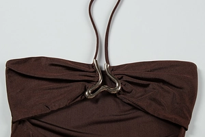 Détail rapproché du haut dos nu marron foncé avec une boucle en métal doré incurvée