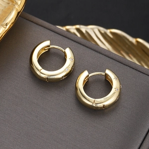 Detail of 18K gold-plated huggie earrings with engraved stars and zircon crystals