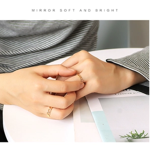 Detail of two golden hollow chain rings stacked on fingers for a modern minimalist look