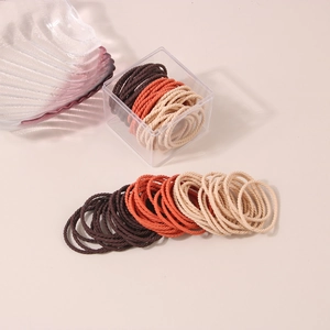 Macro detail of high-elastic woven hair ties in brown and beige tones in a clear box