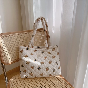 Close-up of quilted bear print tote bag on a woven chair with soft natural lighting
