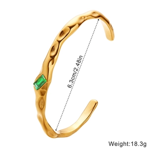Irregular gold titanium steel bangle with green gemstone and hammered texture detail