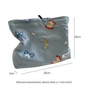 Detailed embroidery of colorful butterflies and flowers on a light blue linen makeup bag
