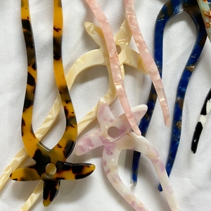 Star-shaped acetate hair fork with tortoiseshell and marble patterns on white fabric