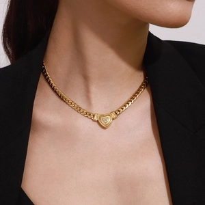 Dettaglio di un ciondolo a cuore vintage dorato con trama radiale e piccoli strass