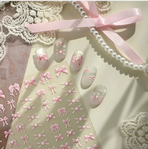Macro view of 3D embossed pink bow nail stickers with elegant pearl accents on lace