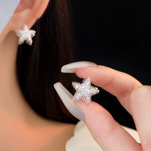 Macro shot of silver zircon star earrings with pavé setting being worn and held
