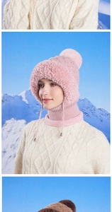 Pink winter knit hood with faux fur trim and pompom detail against a snowy mountain scene