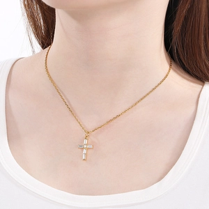 Gros plan d'un collier pendentif croix doré avec zircon et perles porté par un modèle