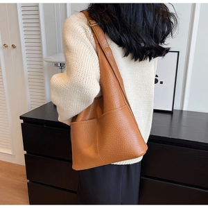 Vue détaillée du sac à bandoulière en cuir grainé marron montrant la texture et le porté