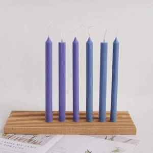 Detailed view of purple and blue ribbed taper candles on a wooden holder