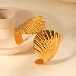 Détail macro d'un bracelet manchette large en acier inoxydable doré 18K motif coquillage