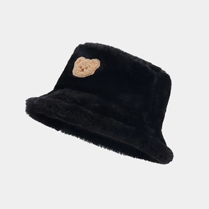 Close-up of a black faux fur bucket hat featuring a cute brown bear plush patch detail