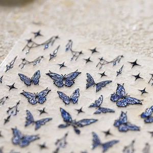 Blue laser butterfly nail stickers with glitter stars and metallic glints on neutral stone