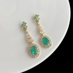 Détail de boucles d'oreilles fleur en zircon vert émeraude sur assiette blanche
