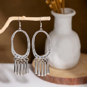 Detail of vintage silver bohemian oval drop earrings with metal tassels on wood branch