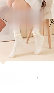 Close-up of cream white cotton mid-calf socks with ribbed texture and slouchy design