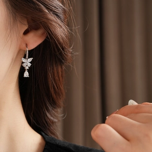 Gros plan des boucles d'oreilles papillon en argent avec cristal goutte sur l'oreille
