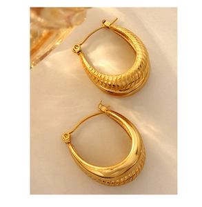 Macro detail of gold U-shaped earrings featuring twisted texture and smooth metal finish