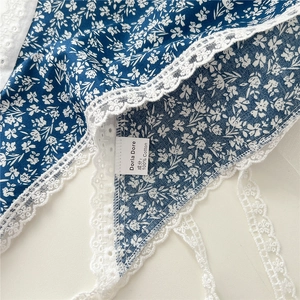 Macro detail of 100% cotton blue floral fabric with elegant white lace embroidery trim