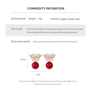 Detailed view of red zircon butterfly pendant earrings with copper and resin accents