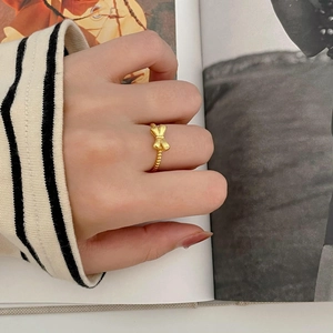 Elegant gold bow ring with beaded band design shown on a stylish fashion background