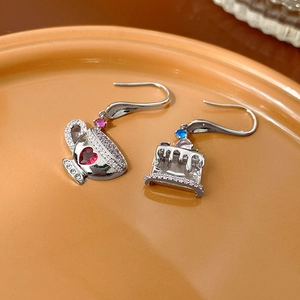 Asymmetric cupcake and teacup earrings with colorful zircon on an orange ceramic plate