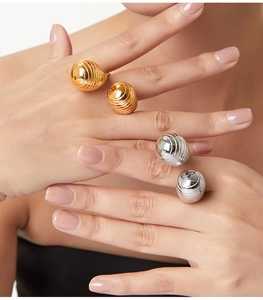 Detailed view of spiral textured gold and silver teardrop rings on model's hand