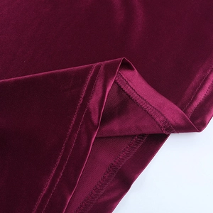 Gros plan détaillé de l'ourlet de robe bordeaux montrant le tissu et la couture