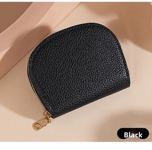 Detail of black pebbled leather texture on half-moon wallet with gold zipper closure