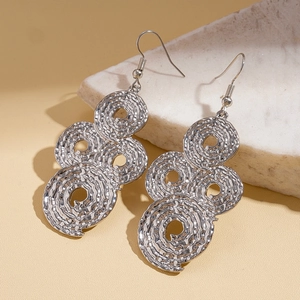 Detail of silver drop earrings with layered spiral rings and hammered metal texture