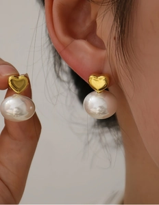 Dettaglio orecchini a cuore in oro 18K con grandi perle barocche lucide indossati