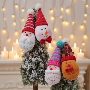 Knitted Christmas ornaments featuring Santa and Snowman hanging on a snowy tree