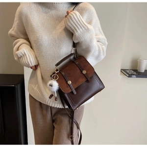 Detailed view of a brown retro square backpack with a cute white plush pendant