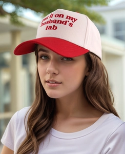 Detailed close-up of embroidery text on a red and white cotton trucker baseball cap