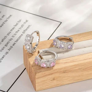 Silver hoop earrings with square purple and pink zircons on a wooden display stand