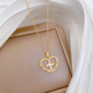 Elegant gold heart pendant necklace with cross detail and crystals on silk background