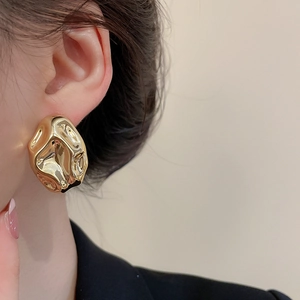 Dettaglio di un orecchino a perno dorato a forma di lava per un look moderno e chic