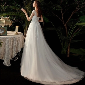 Elegant white lace wedding dress with V-neck open back and long trailing skirt in forest