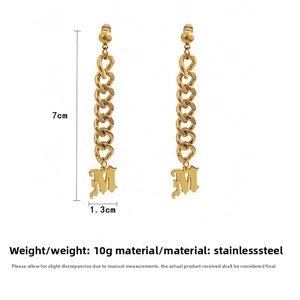 Détail de boucles d'oreilles chaîne gourmette dorée avec pendentif M, acier inoxydable